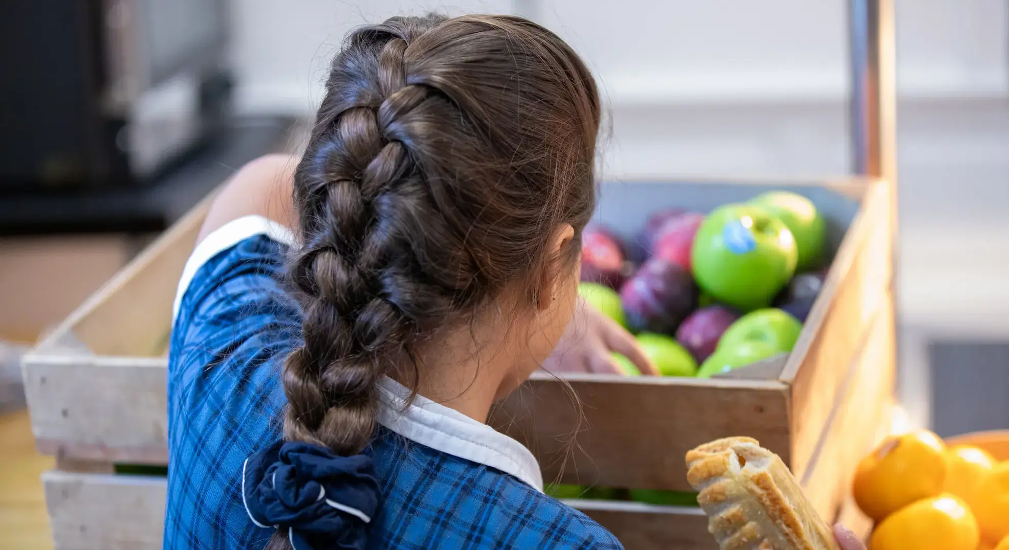 Student picking a piece of fruit from a crate
