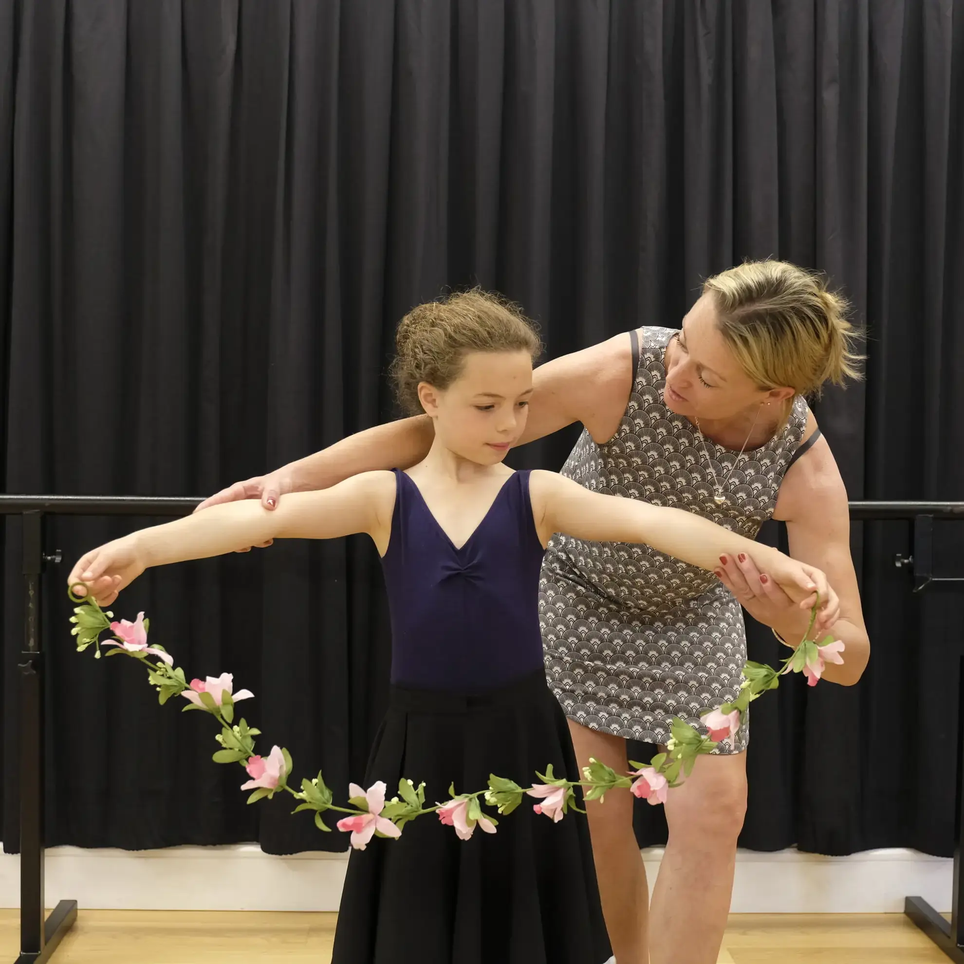 Student spreading garland of flowers with help from teacher