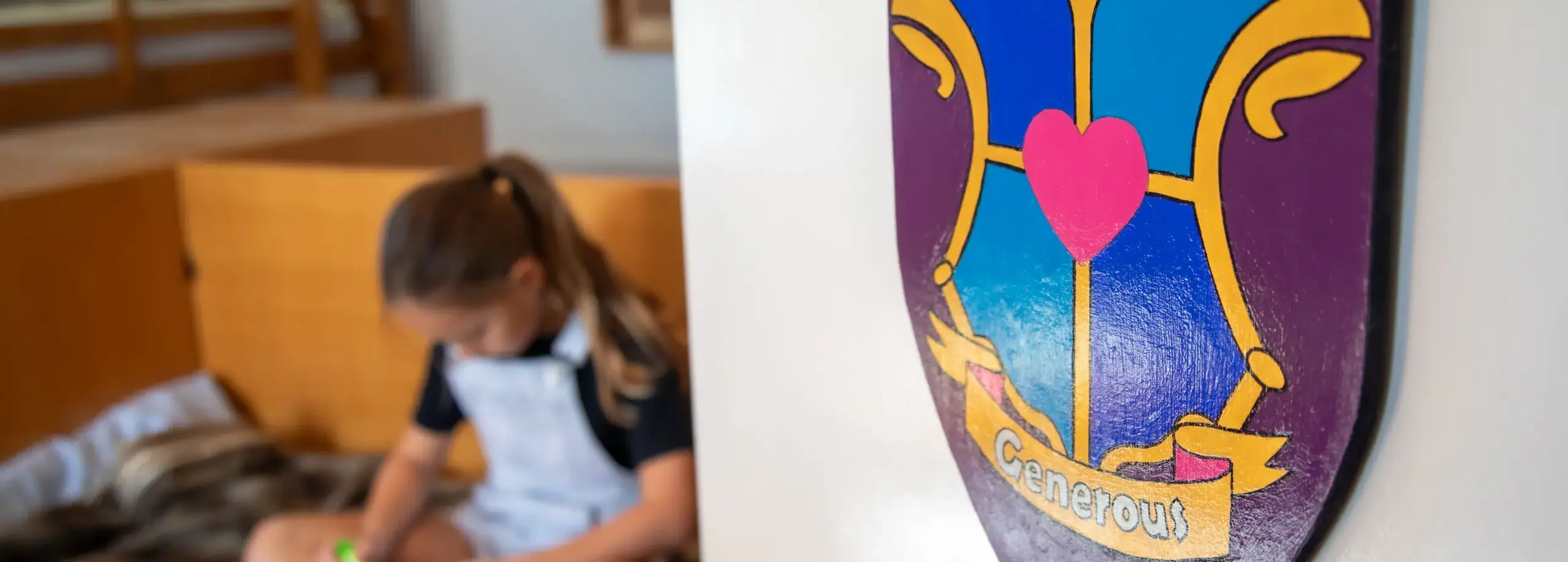 Student sitting on bed, with the crest of her House in the foreground