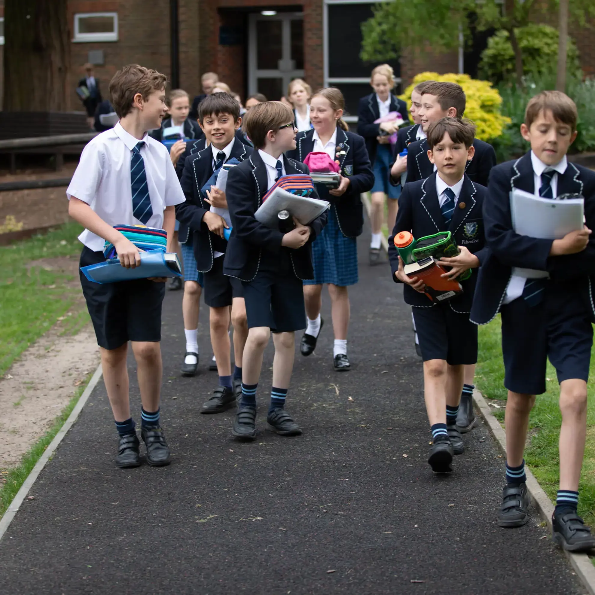 Students walking along a path, carrying books and folders