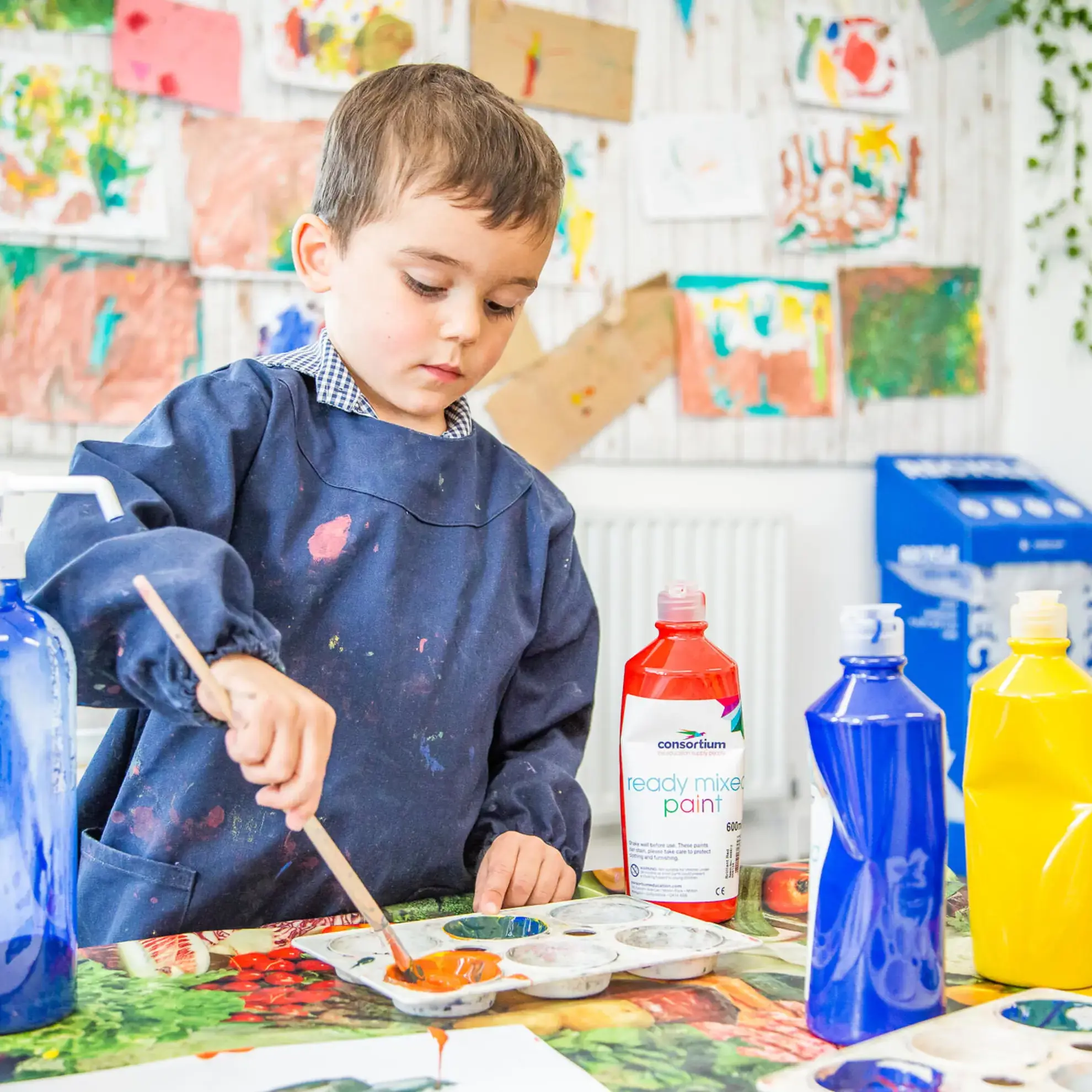 Student painting, wearing apron