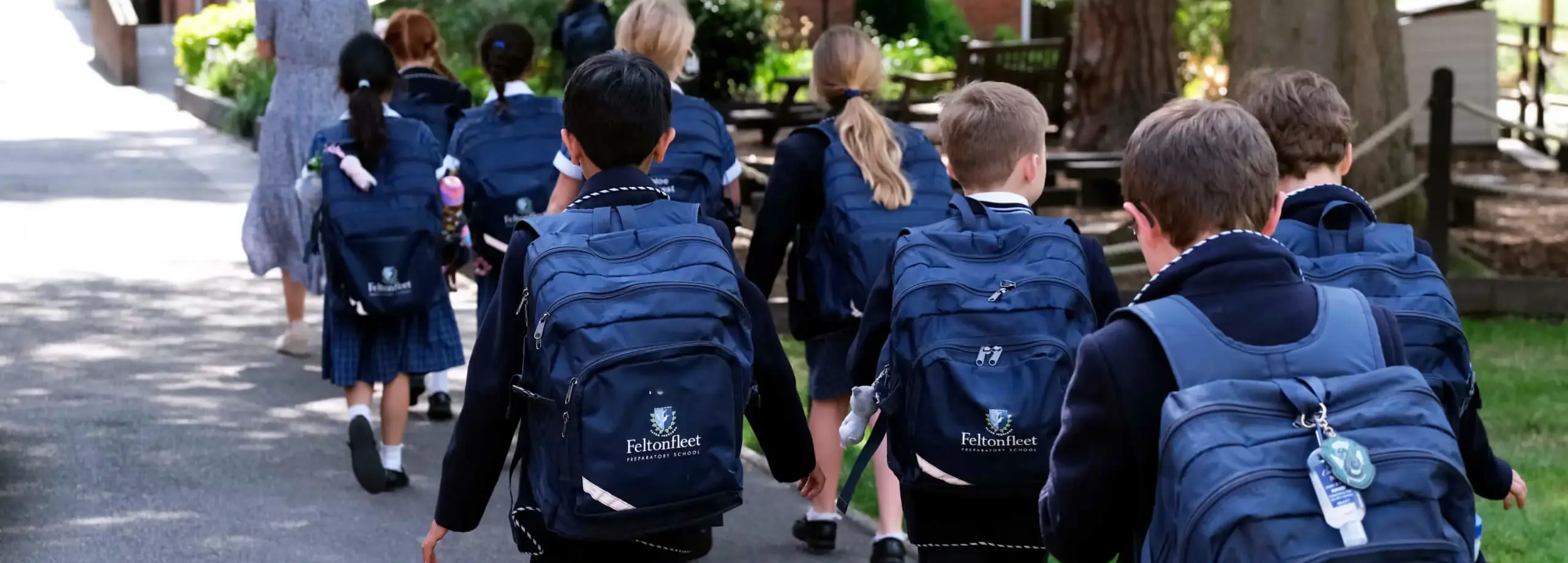 Pupils walking with rucksacks, photographed from behind, at Feltonfleet private school Surrey