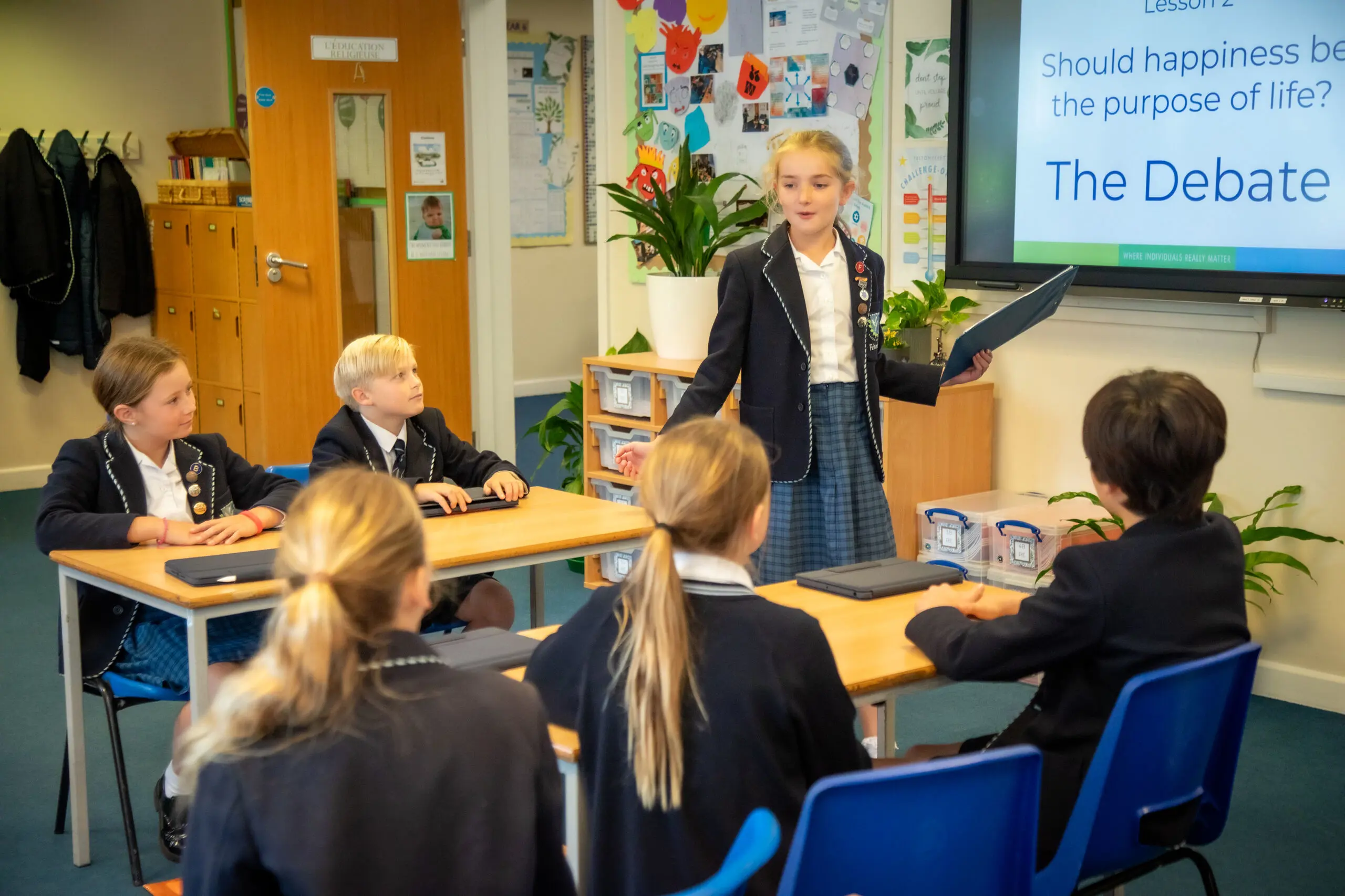 Student presenting to rest of class, holding a laptop