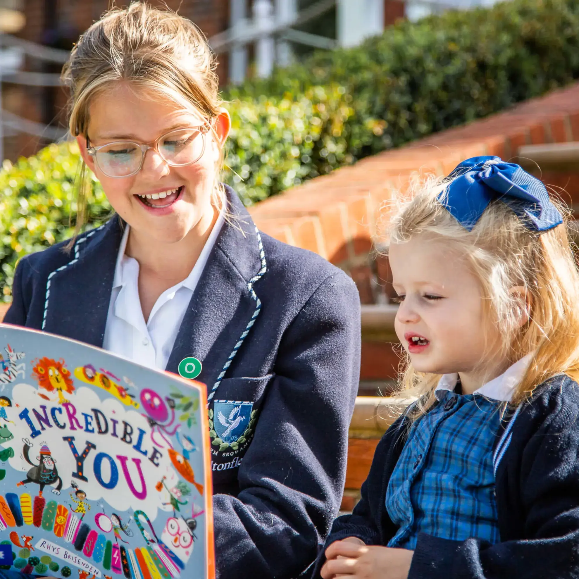 Older student reading to younger peer
