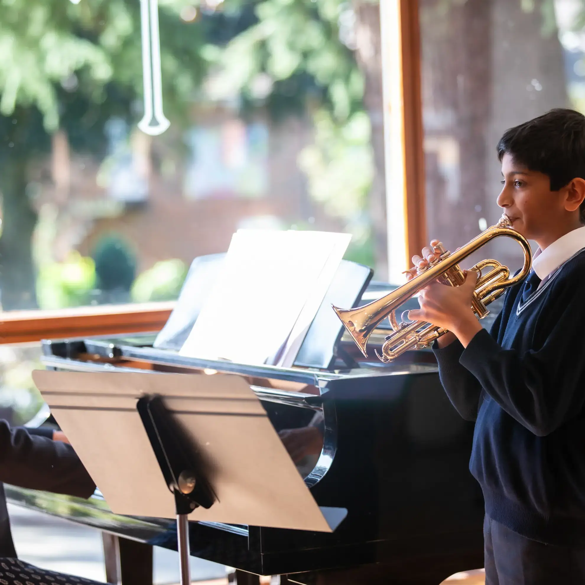 Student playing cornet in front of piano