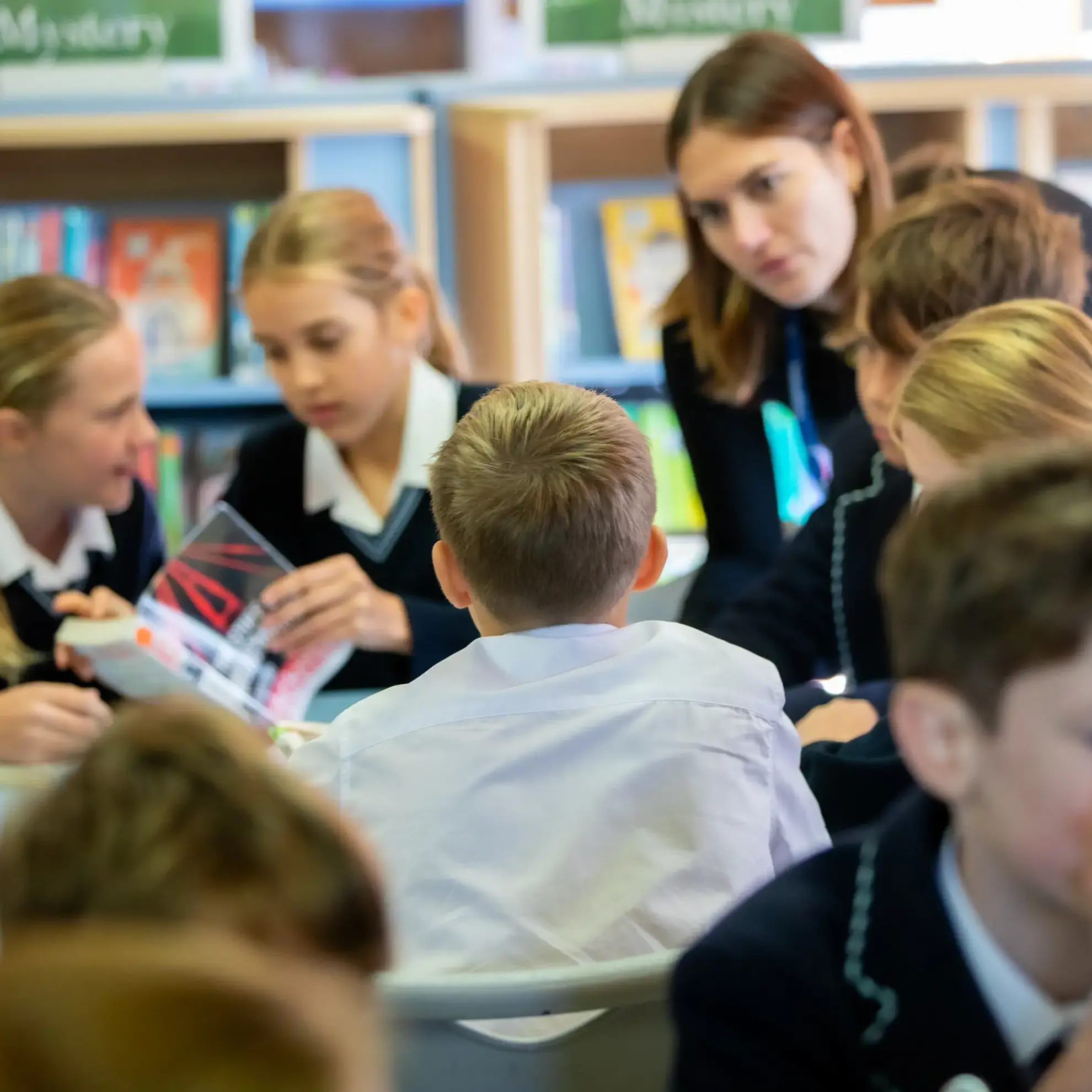 Students working in library under supervision from tutor