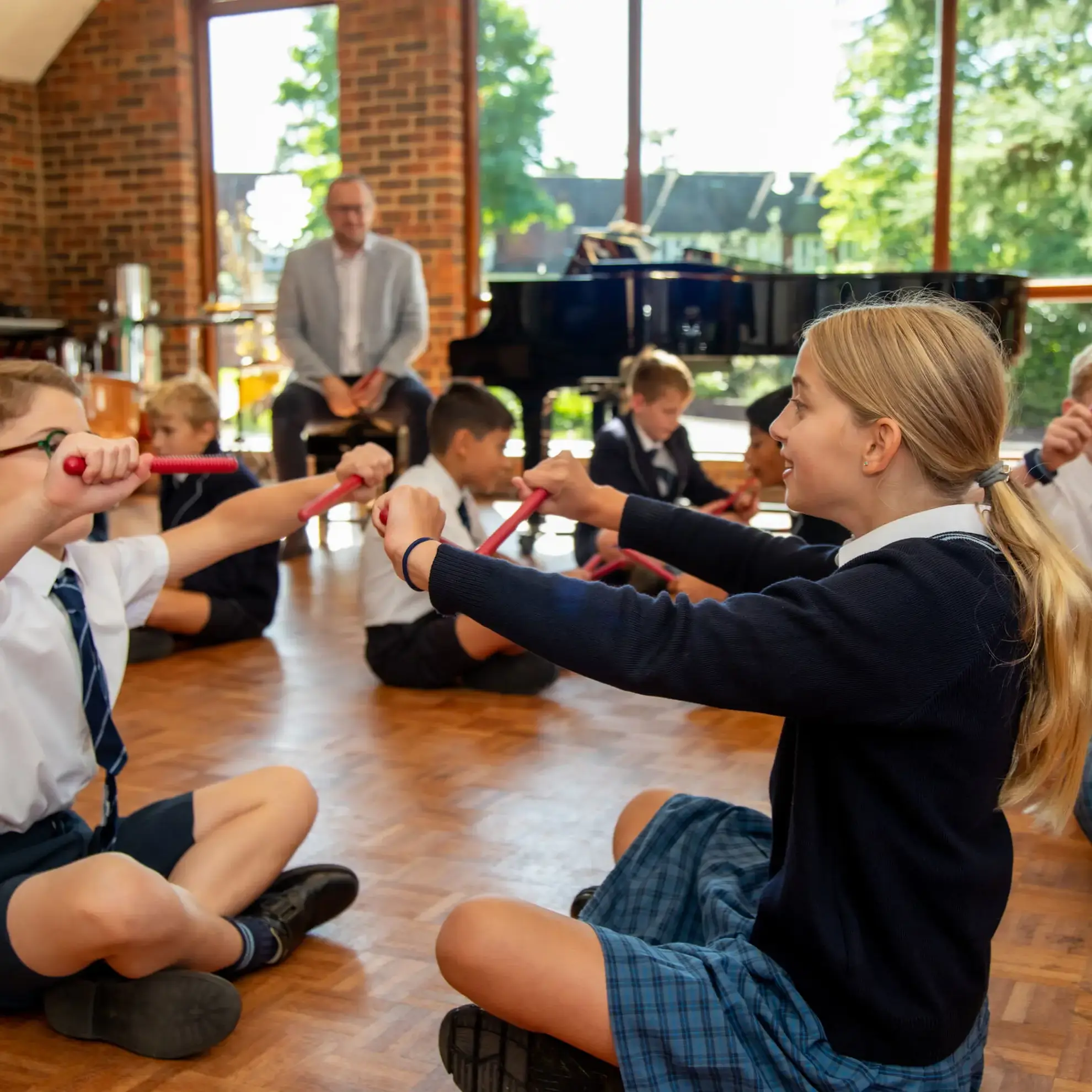 Students learning rhythms, sitting on floor