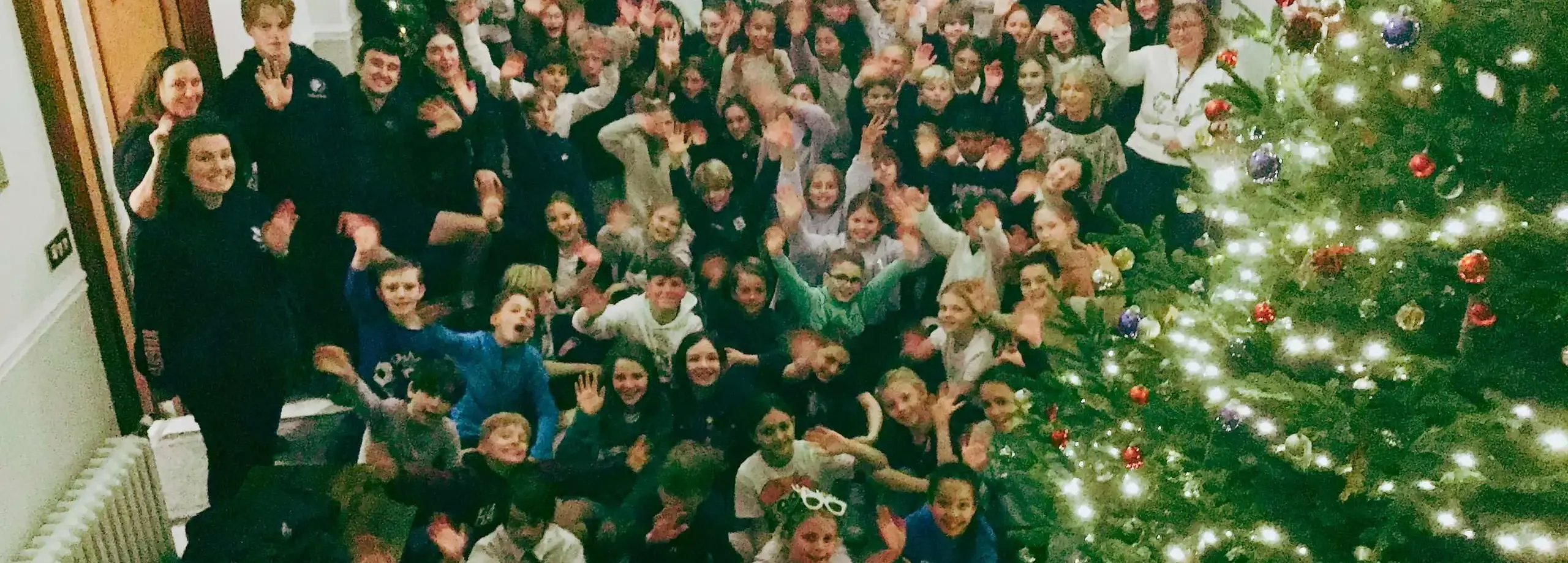 Staff and pupils posing in front of a Christmas tree