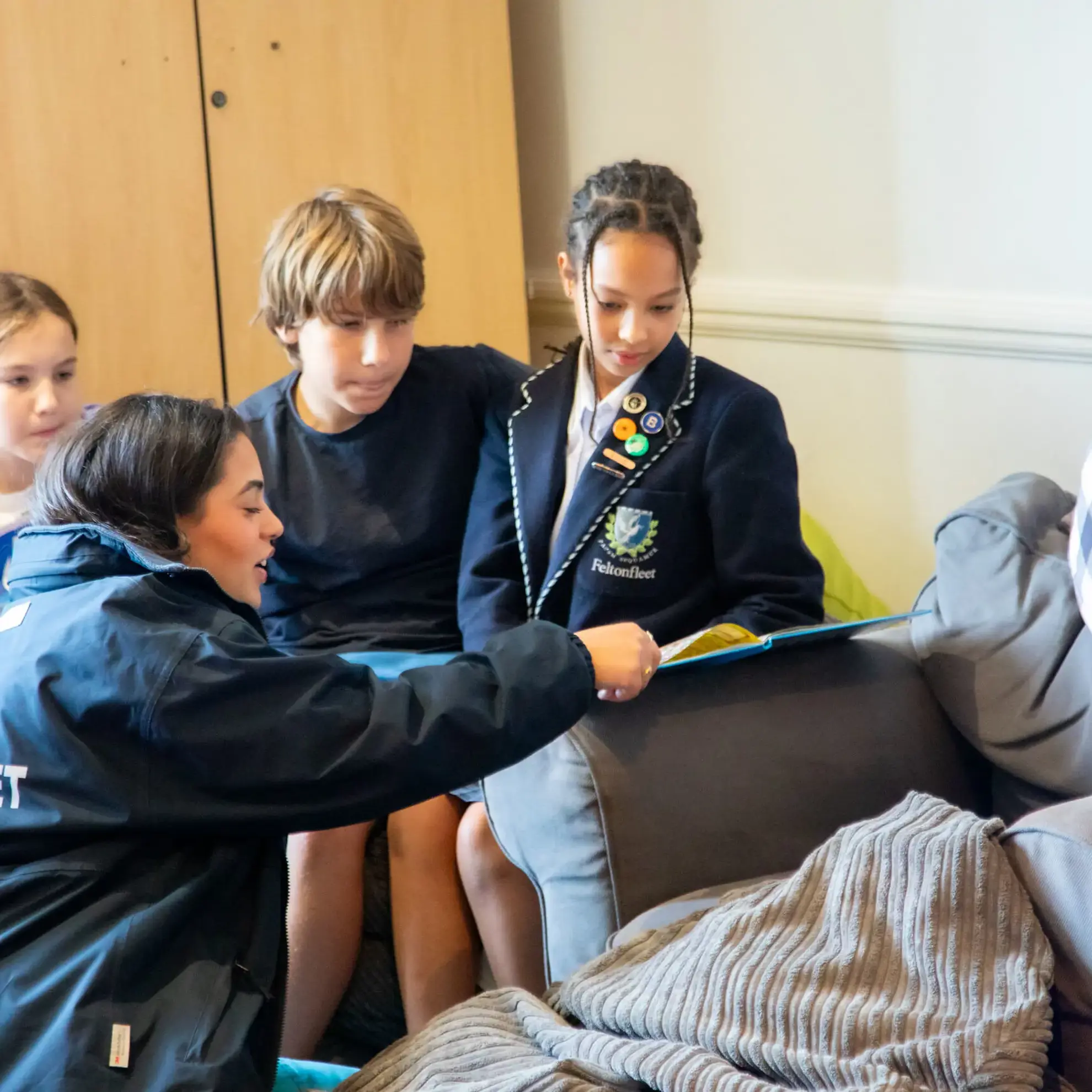 Boarding staff member pointing at book in front of three pupils